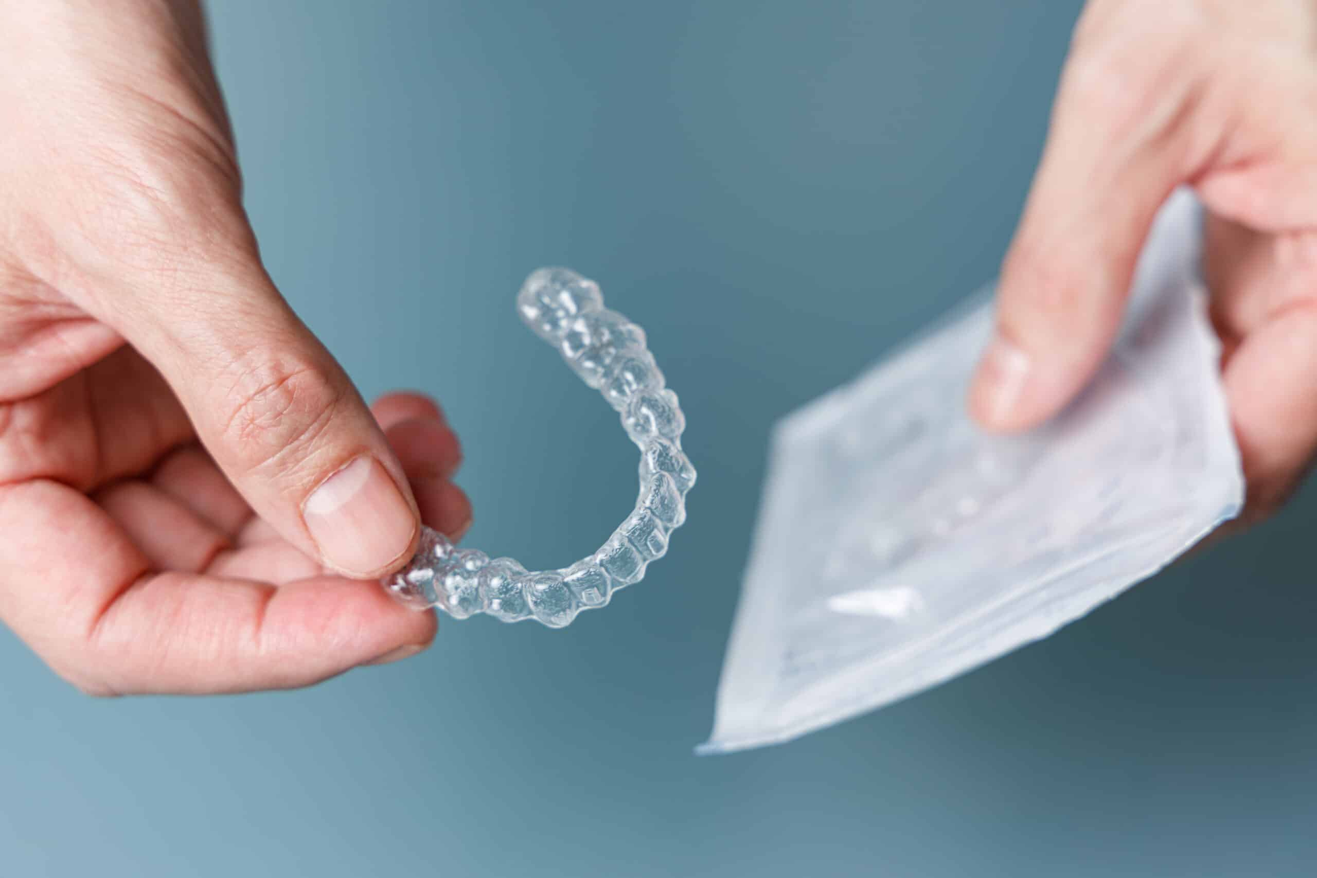 Man holding transparent aligner and its package. Invisalign orthodontics concept